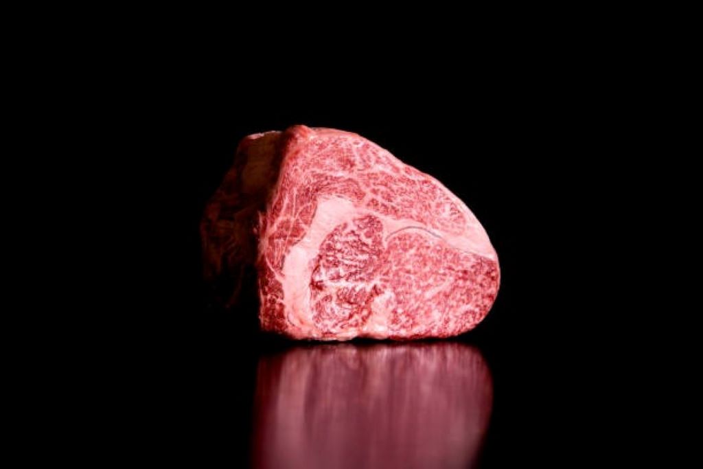 A close-up of a raw Japanese A5 Wagyu steak, showing its intense white marbling on a dark background