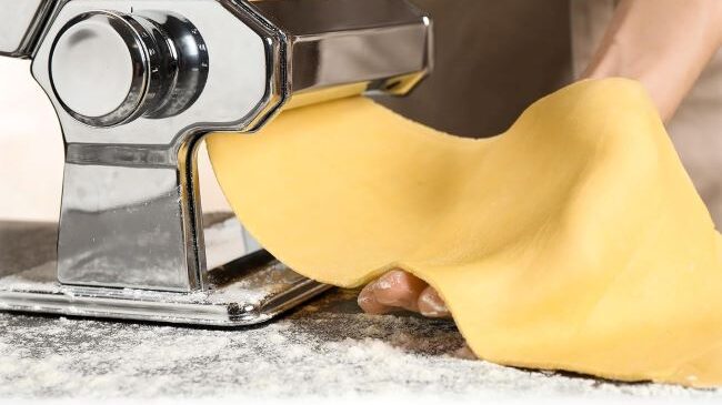 Close-up of a 2-in-1 pasta machine rolling dough, ideal for home cooking upgrades.